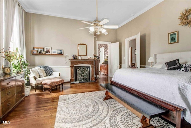 bedroom with a fireplace, crown molding, and wood finished floors