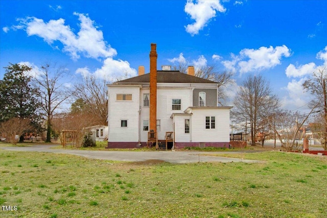 back of property featuring a lawn and a chimney