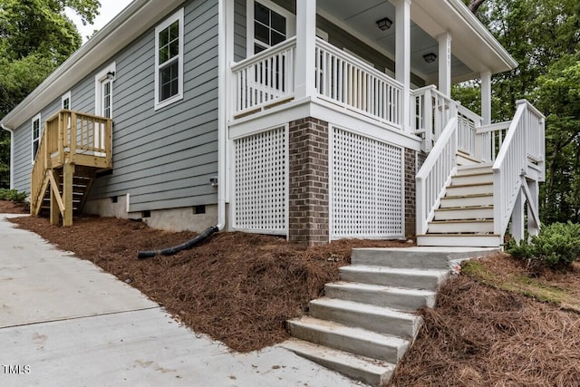 view of side of home featuring stairs, brick siding, and crawl space