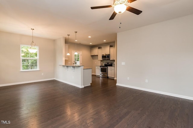 unfurnished living room featuring a ceiling fan, baseboards, recessed lighting, dark wood-style flooring, and a sink