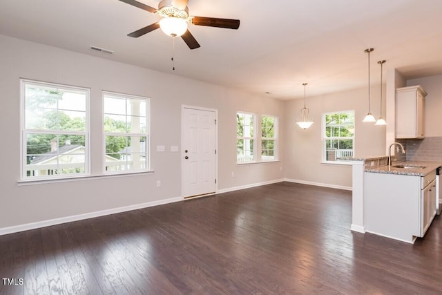 unfurnished living room with a sink, visible vents, baseboards, and dark wood-type flooring