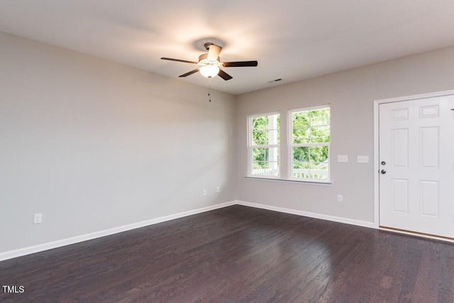 spare room featuring baseboards, dark wood-type flooring, and a ceiling fan