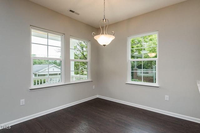 empty room featuring dark wood-style floors, baseboards, and a healthy amount of sunlight