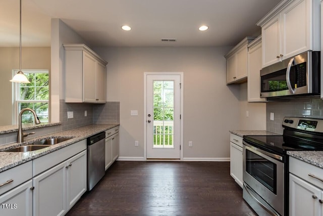 kitchen with light stone counters, baseboards, dark wood-style flooring, a sink, and appliances with stainless steel finishes