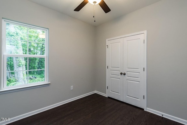 unfurnished bedroom featuring dark wood-type flooring, baseboards, a closet, and ceiling fan