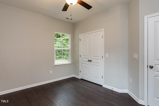 unfurnished bedroom featuring dark wood finished floors, visible vents, baseboards, and a ceiling fan