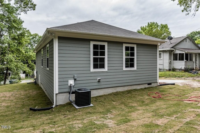 back of house featuring central air condition unit, a lawn, and a shingled roof