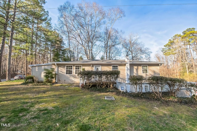 view of front of property with a chimney, a deck, and a front yard