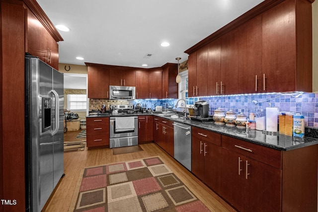 kitchen with light wood-style flooring, recessed lighting, a sink, appliances with stainless steel finishes, and backsplash