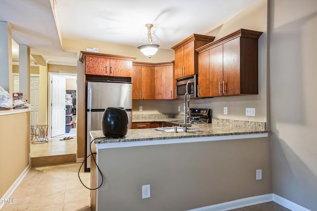 kitchen featuring stone counters, baseboards, appliances with stainless steel finishes, and a peninsula