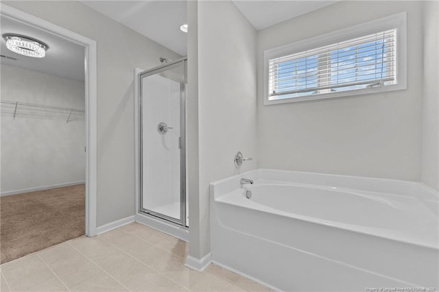 bathroom with tile patterned flooring, a stall shower, a spacious closet, and a bath