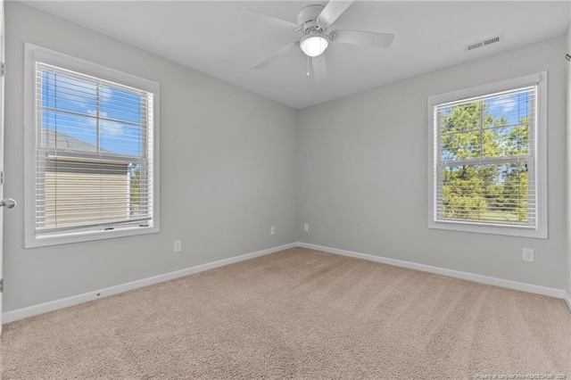 carpeted spare room with visible vents, a ceiling fan, and baseboards