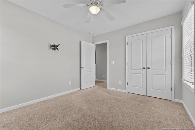 unfurnished bedroom with light carpet, ceiling fan, a closet, and baseboards