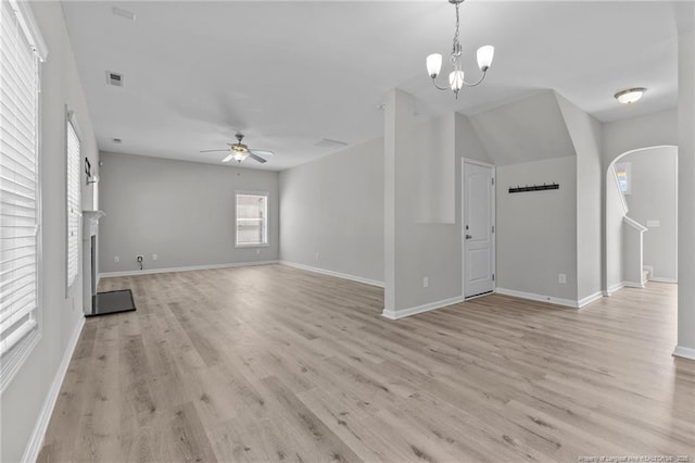 unfurnished living room with visible vents, light wood finished floors, baseboards, a fireplace, and ceiling fan with notable chandelier