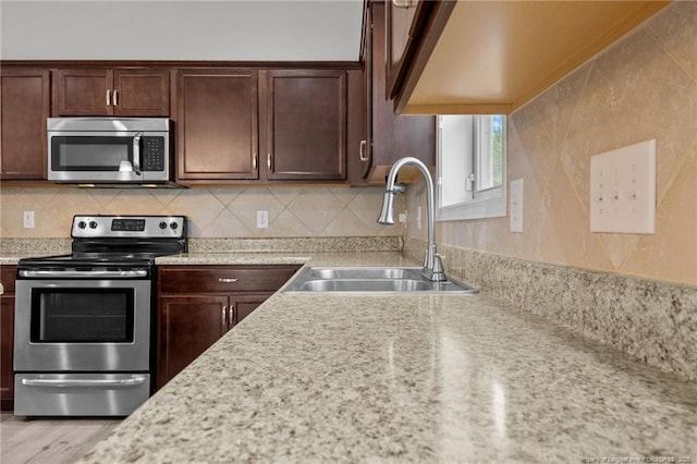 kitchen featuring a sink, dark brown cabinets, tasteful backsplash, and stainless steel appliances