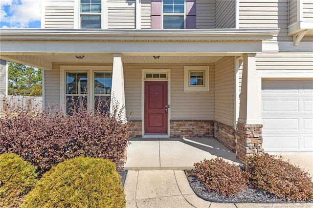 entrance to property with stone siding, covered porch, and a garage