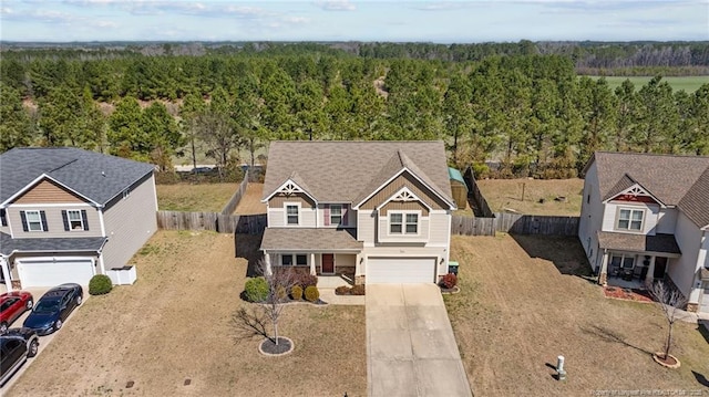 view of front of property featuring fence, a forest view, a garage, and driveway