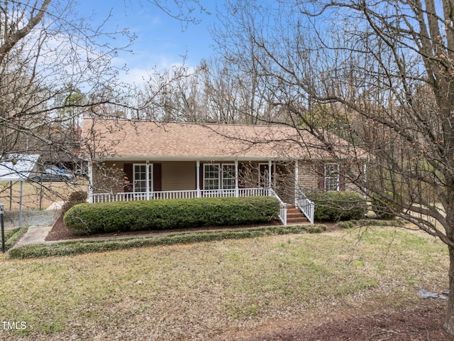 single story home featuring roof with shingles, covered porch, and a front yard