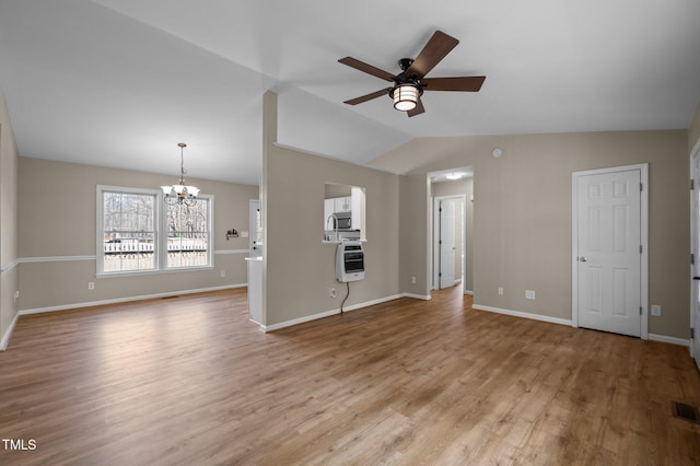 unfurnished living room featuring ceiling fan with notable chandelier, baseboards, light wood-style flooring, and lofted ceiling