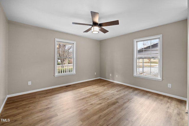 empty room with baseboards, ceiling fan, and wood finished floors