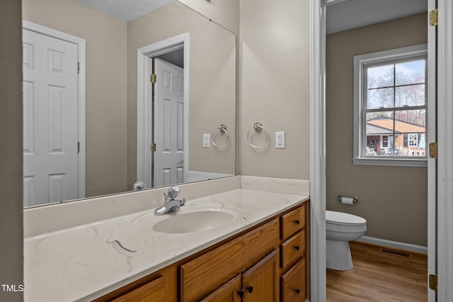 bathroom featuring visible vents, toilet, wood finished floors, baseboards, and vanity