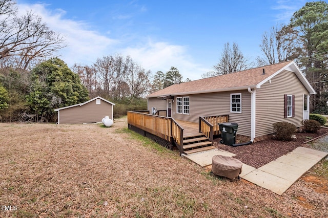 rear view of property featuring a lawn, a shingled roof, and a deck