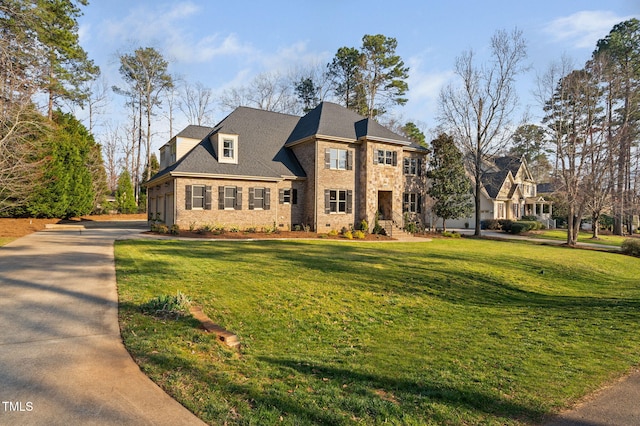 view of front facade with brick siding, concrete driveway, and a front lawn