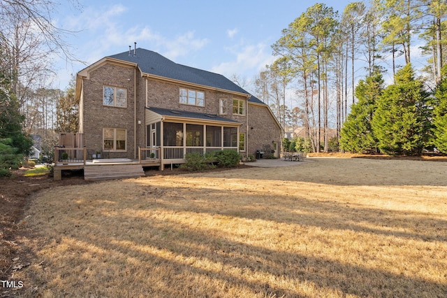 back of house with brick siding, a sunroom, a deck, a yard, and a patio