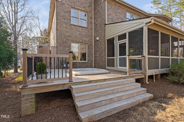 rear view of property with a deck, brick siding, and a sunroom