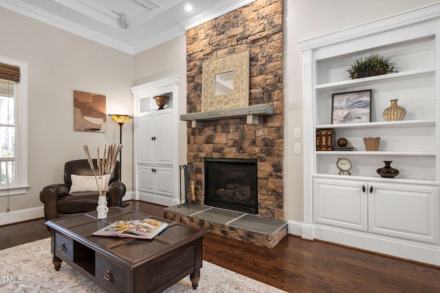 living area with ornamental molding, built in features, wood finished floors, a fireplace, and baseboards