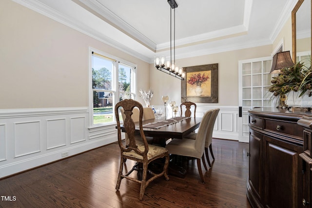 dining area with dark wood-style floors, a wainscoted wall, crown molding, and a raised ceiling