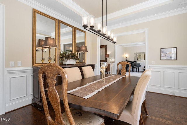 dining space with a decorative wall, wainscoting, dark wood-type flooring, and an inviting chandelier