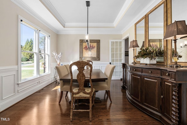 dining room featuring a tray ceiling, visible vents, a wainscoted wall, and dark wood-style flooring