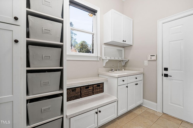 laundry area with a sink, baseboards, and light tile patterned flooring