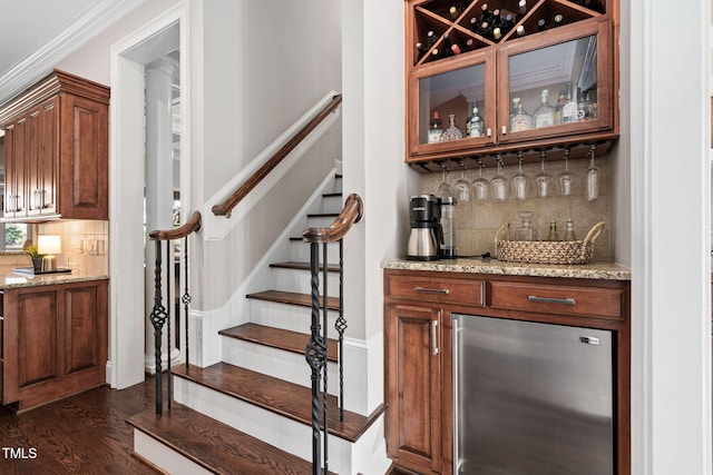 bar with stairway, dark wood finished floors, ornamental molding, a bar, and backsplash