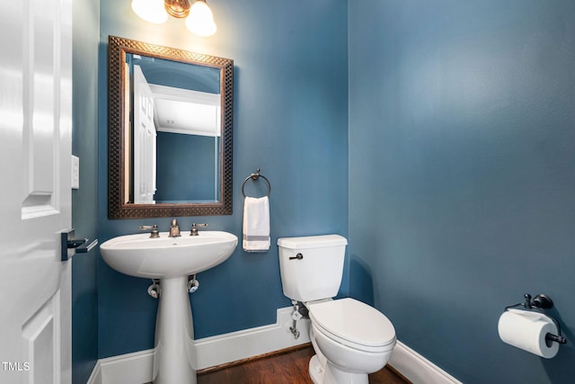 bathroom with toilet, baseboards, and wood finished floors