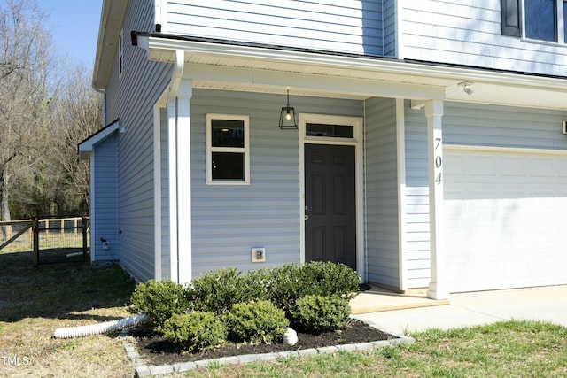 doorway to property with an attached garage and fence