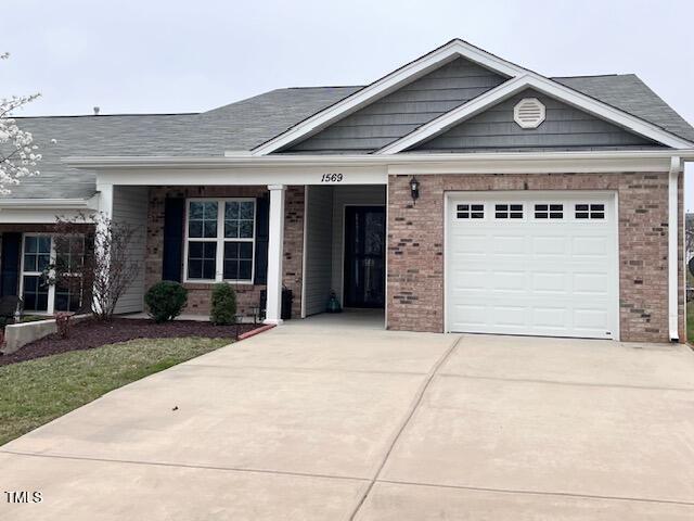 ranch-style house with brick siding, concrete driveway, a garage, and roof with shingles