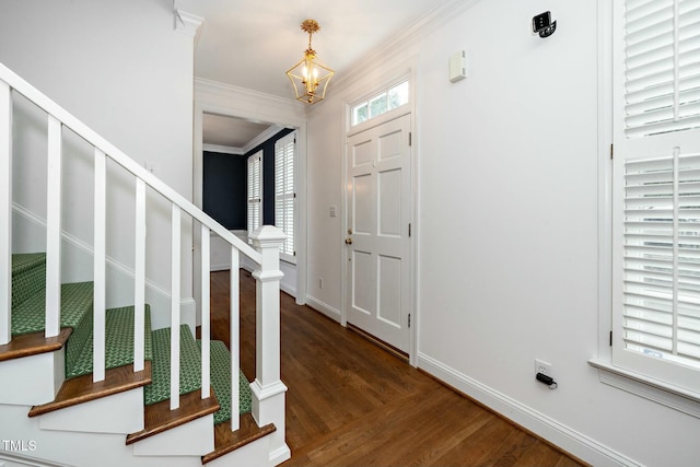 foyer entrance with baseboards, stairway, ornamental molding, an inviting chandelier, and wood finished floors