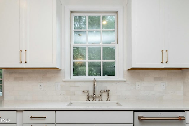 kitchen with a sink, dishwashing machine, backsplash, and white cabinets