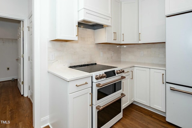 kitchen featuring light countertops, custom range hood, decorative backsplash, white cabinets, and white appliances