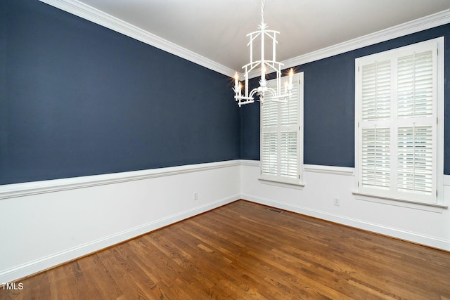 spare room featuring visible vents, a wainscoted wall, a notable chandelier, wood finished floors, and crown molding