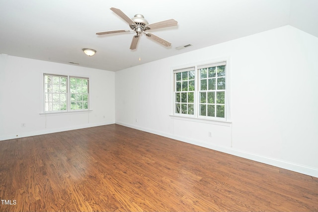 empty room featuring visible vents, ceiling fan, baseboards, dark wood finished floors, and vaulted ceiling