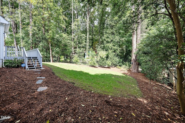 view of yard featuring a forest view and a wooden deck