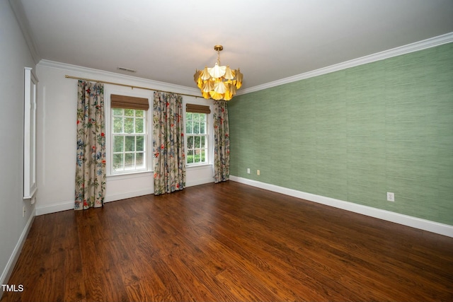 spare room featuring wood finished floors, baseboards, visible vents, ornamental molding, and a chandelier