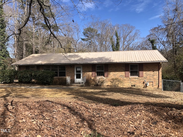 rear view of property featuring metal roof, brick siding, and fence