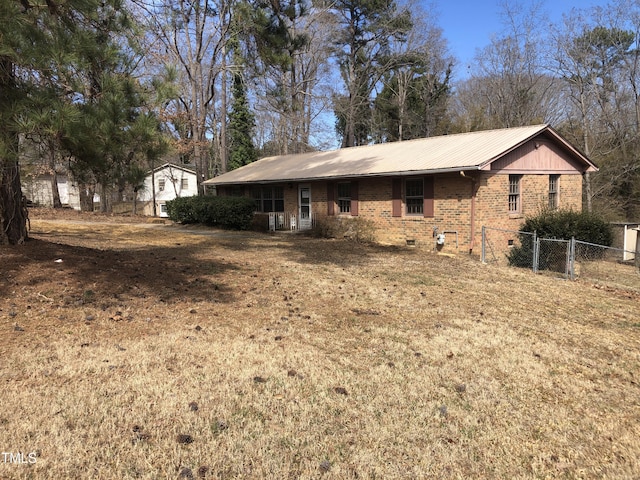 exterior space with a front yard, fence, crawl space, brick siding, and metal roof