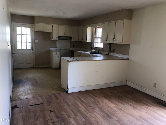 kitchen with white cabinetry, a peninsula, wood finished floors, and under cabinet range hood