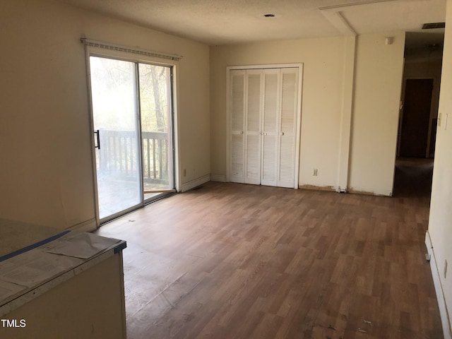 unfurnished bedroom with access to exterior, baseboards, a closet, and wood finished floors