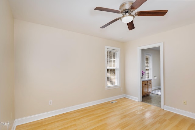 empty room with visible vents, a ceiling fan, light wood-type flooring, and baseboards